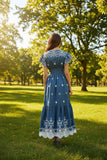 Blue embroidered dress with white details on a neutral background